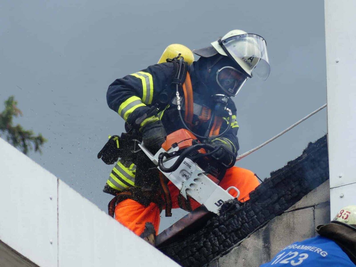Mit einer Motorsäge entfernt ein Feuerwehrmann Teile der verkohlten Fassade. Foto: him