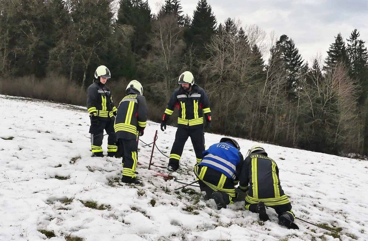 Feuerwehrleute schlagen große Stahlnägel in die Wiese.