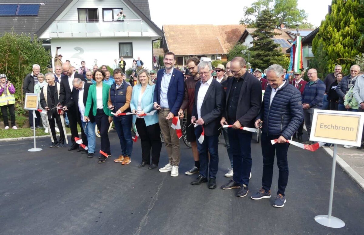 Bescheiden im Hintergrund: Tiefbauamtsleiter Konrad Ginter links hinter dem "Ortsschild Eschbronn" bei der Radwegeröffnung am  23.September. Am Band (von links): Pfarrer Dr. Eberhard Eisele, Pfarrer Markus Krimmer, BI Vorsitzender Thomas Maier, Oberbürgermeisterin Dorothee Eisenlohr, Abteilungspräsident Karl Kleemann, Bundestagsabgeordnete Maria-Lena Weiss, Landtagsabgeordneter Daniel Karrais, Radbeauftragter Gunnar Link, Bürgermeister Franz Moser, Landtagsabgeordneter Stefan Teufel und Dezernent Gerald Kramer.
Foto: him