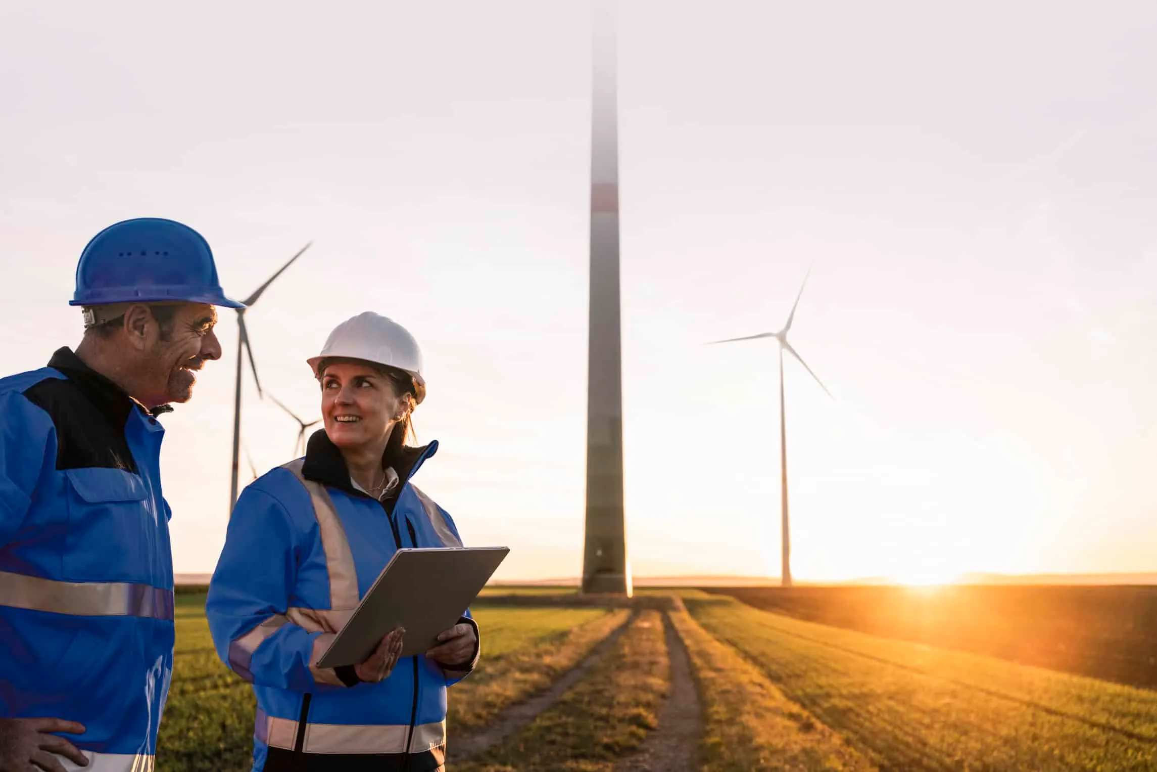 engineers wearing hardhats discussing at sunset