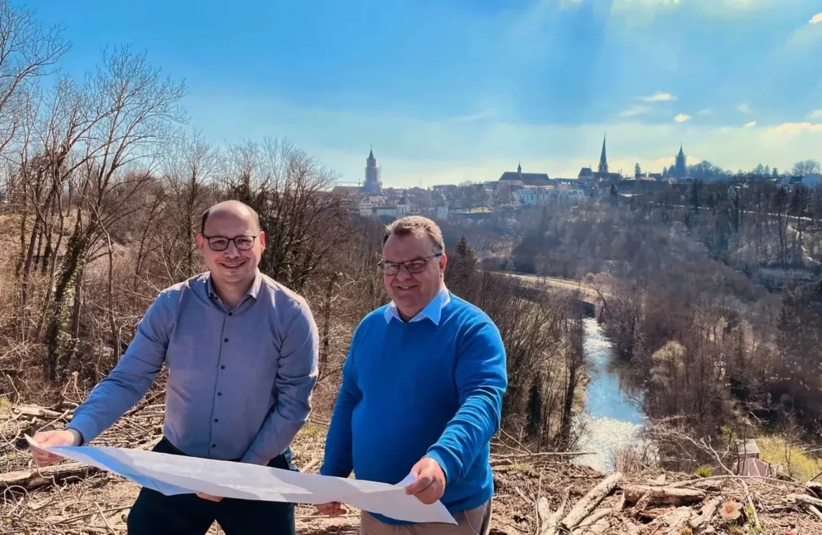 Oberbürbermeister Dr. Christian Ruf und Projektleiter Roland Haag stehen an der Stelle, wo der 60 Meter hohe Pylon für die Hängebrücke „NECKAR LINE“ errichtet wird. Im Hintergrund ist das Neckartal und die historische Innenstadt von Rottweil zu sehen (Foto: Stadt Rottweil / Stengelin).