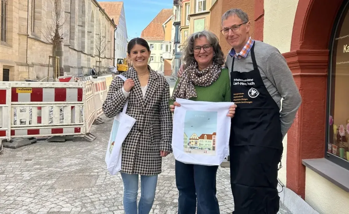 Gemeinsam für die Innenstadt: Schuhmachermeister Karl-Heinz Auch mit Bettina Auch und Lorena Moosmann (von rechts) vom Stadtmarketing präsentieren die Stofftaschen, die bei der Aktion „Ich packe meine Tasche….“ verteilt werden. Die Sanierung der Bruderschaftsgasse ist weit fortgeschritten, am Samstag, 10 Mai, wird die Eröffnung gefeiert (Foto: Stadt Rottweil / Strasser).