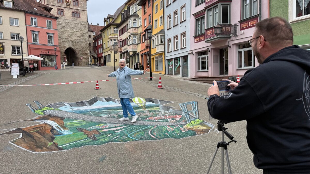 Posiert mit Freude für ein Handyfoto, das Street-Art-Künstler Benzing anfertigt: eine Passantin auf der 3D-Hängebrücke in Rottweil. Foto: Peter Arnegger