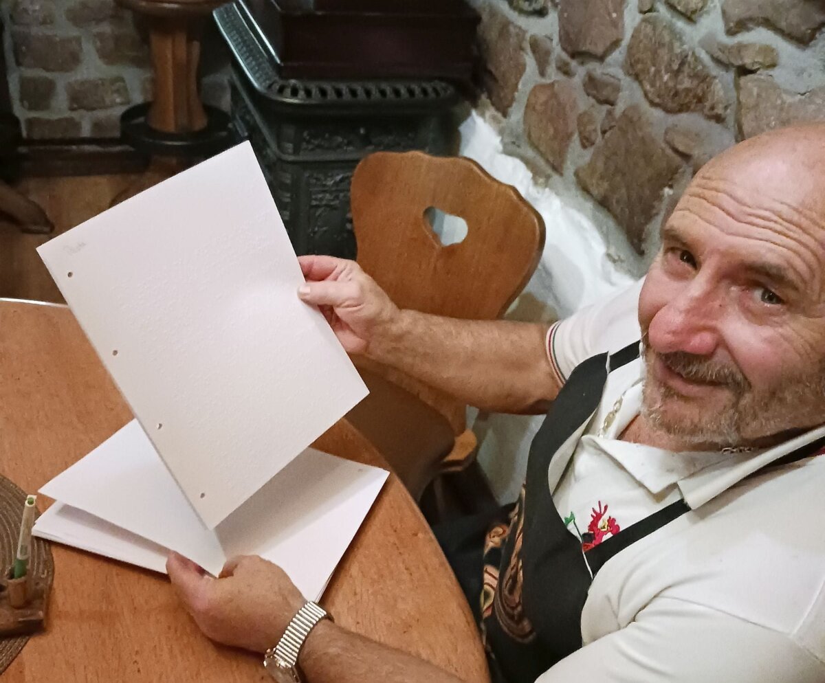 Francesco Infantone mit seiner Speisekarte in Blindenschrift. Foto: him