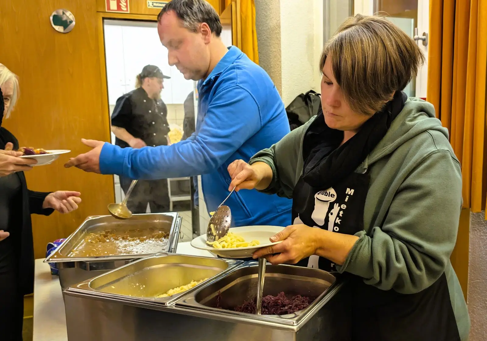 Die ehrenamtlichen Helfer versorgen die Gäste mit Gulasch, Spätzle und Blaukraut. Im Hintergrund koordiniert Simon Lauble die Arbeit in der Küche.  Foto: Stadt