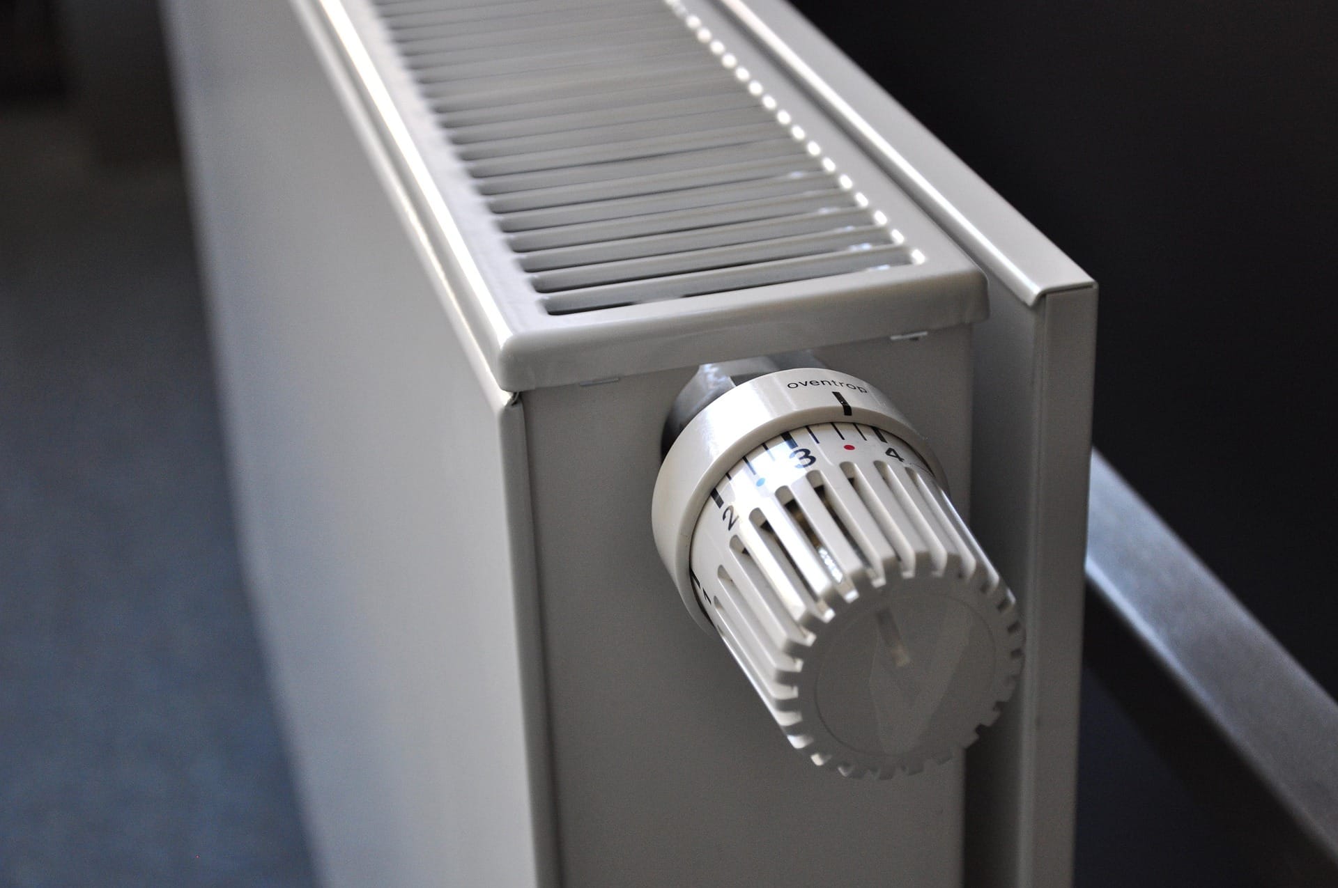 Weißer Heizkörper mit einem Thermostat zur Temperaturregelung.