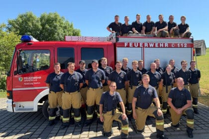 Feuerwehrleute der Abteilung Stetten posieren vor ihrem roten Einsatzfahrzeug.