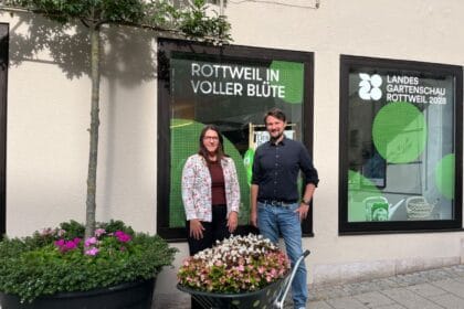 Personen bei Rottweil in voller Blüte vor Schaufenster der Landesgartenschau 2028. Pflanzkübel im Vordergrund.