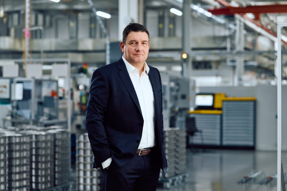 Geschäftsmann im Anzug steht in moderner Industrieanlage, repräsentiert Fertigungsindustrie und Unternehmensführung.