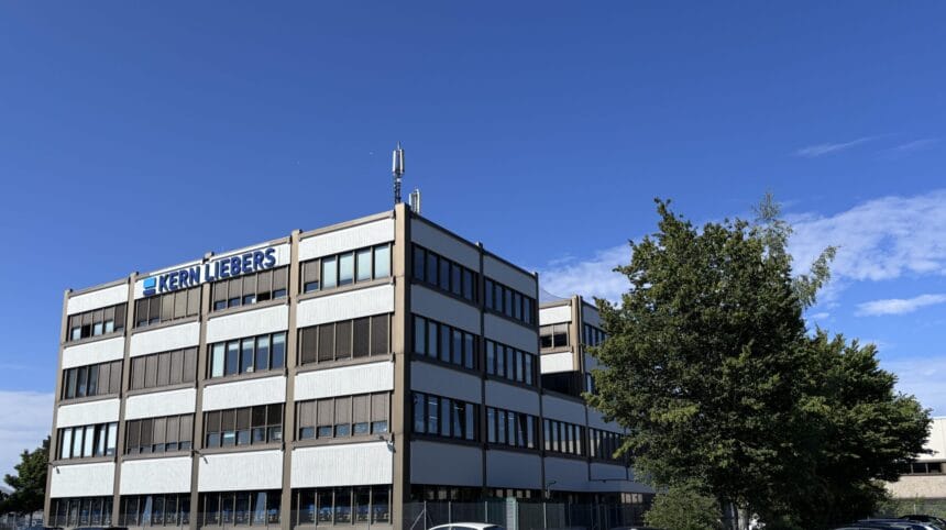 Modernes Bürogebäude mit Kern Liebers Logo, blauer Himmel, grüne Bäume, industrieller Standort.