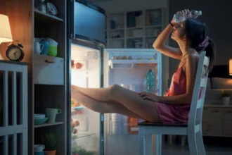 woman cooling herself in front of the open fridge