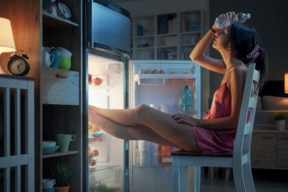 woman cooling herself in front of the open fridge