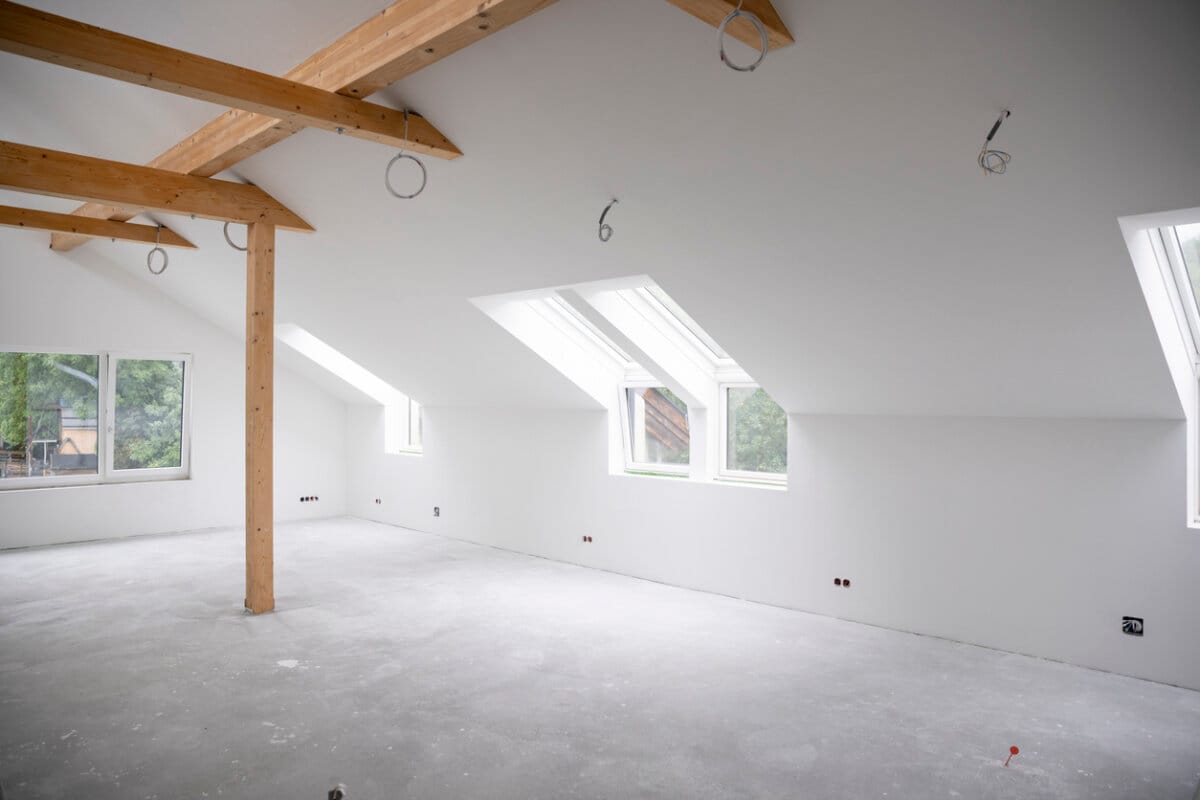 attic construction site freshly painted, the floor is still screed, walls are white