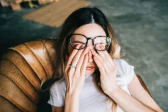 young woman rubs her eyes after using glasses. eye pain or fatigue concept.
