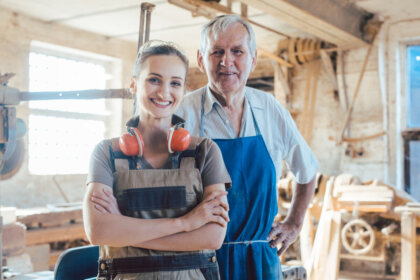 senior master carpenter with his granddaughter in the wood workshop