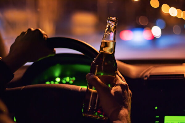 man drink beer while driving at night in the city. dangerously driving